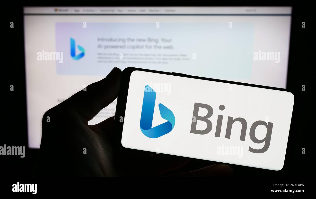 Person holding smartphone with logo of web search engine Microsoft Bing on screen in front of website. Focus on phone display. Stock Photo