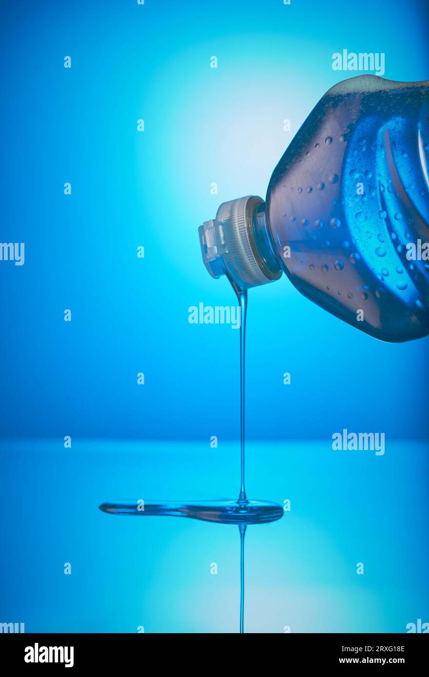 Bottle of washing up Liquid tilting downwards with liquid running out