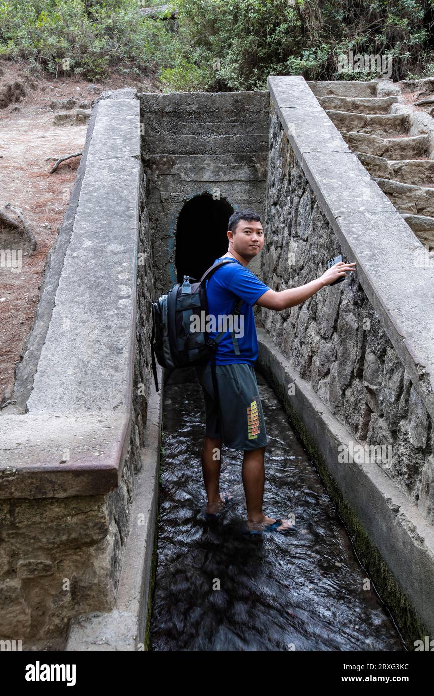 Tourist walks into the walk-in tunnel, Epta Piges - The Seven Springs