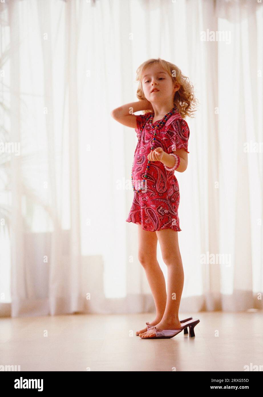 Little girl with way too big shoes plays big lady digital and KB slide Stock Photo