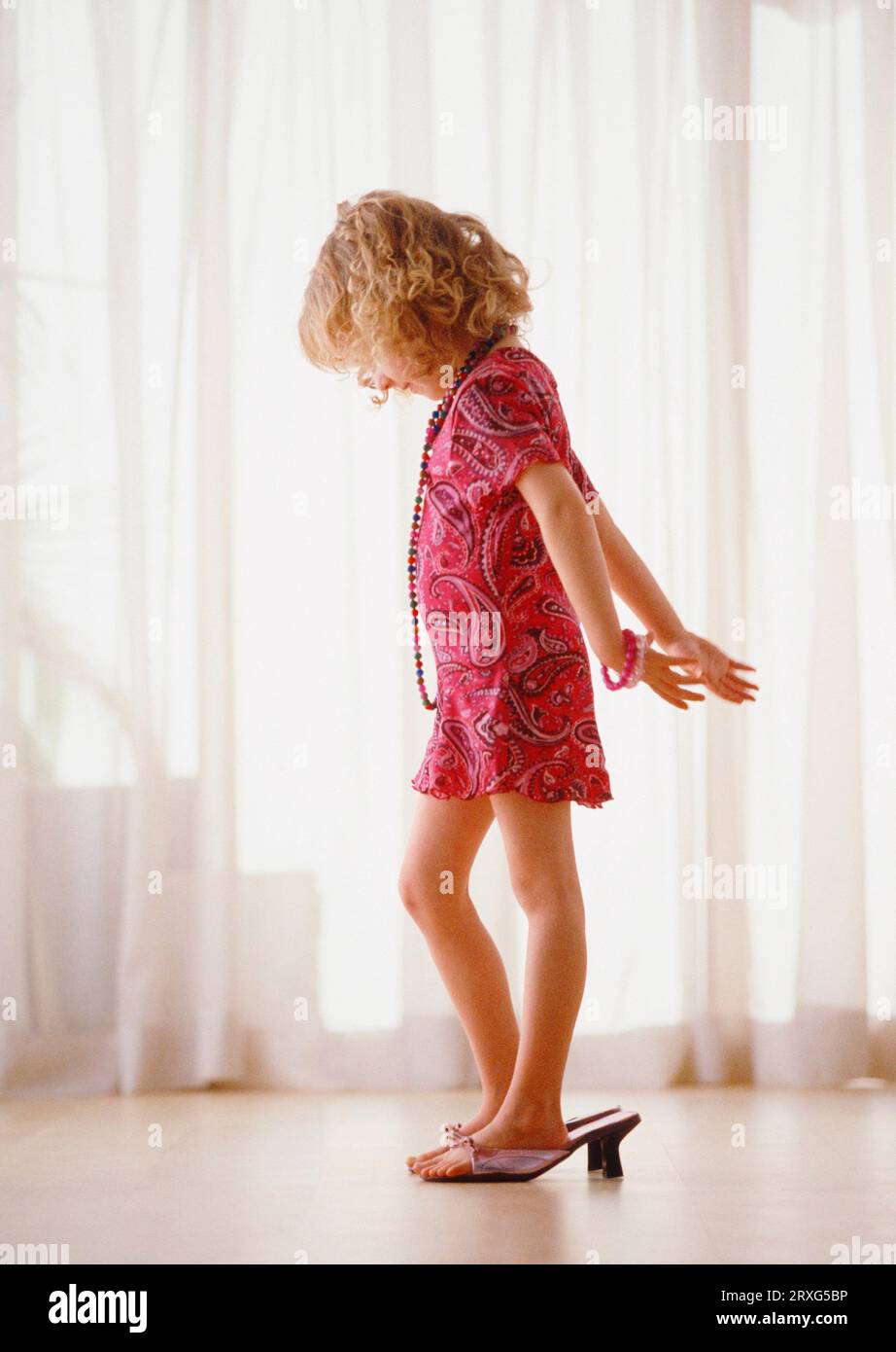 Little girl with way too big shoes plays big lady digital and KB slide Stock Photo