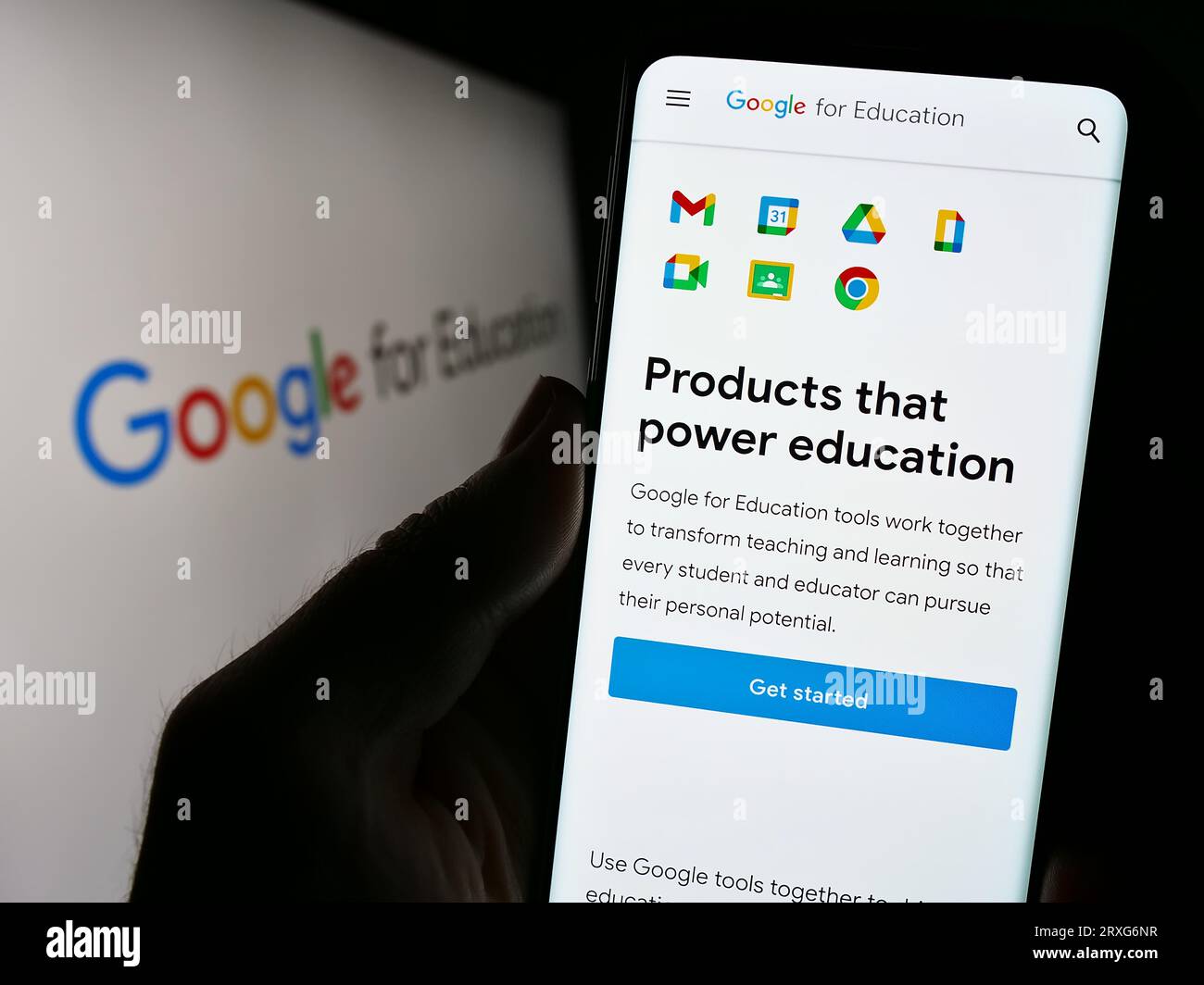 Person holding cellphone with webpage of software product Google for Education on screen in front of logo. Focus on center of phone display. Stock Photo