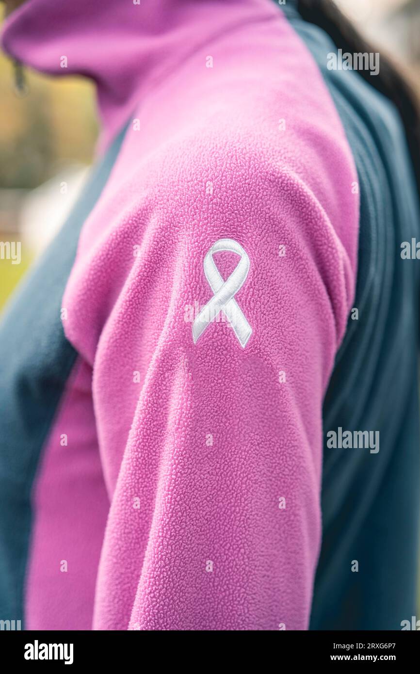 Side view of a woman wearing a sweatshirt with an embroidered cancer awareness ribbon. Vertical Shot Stock Photo