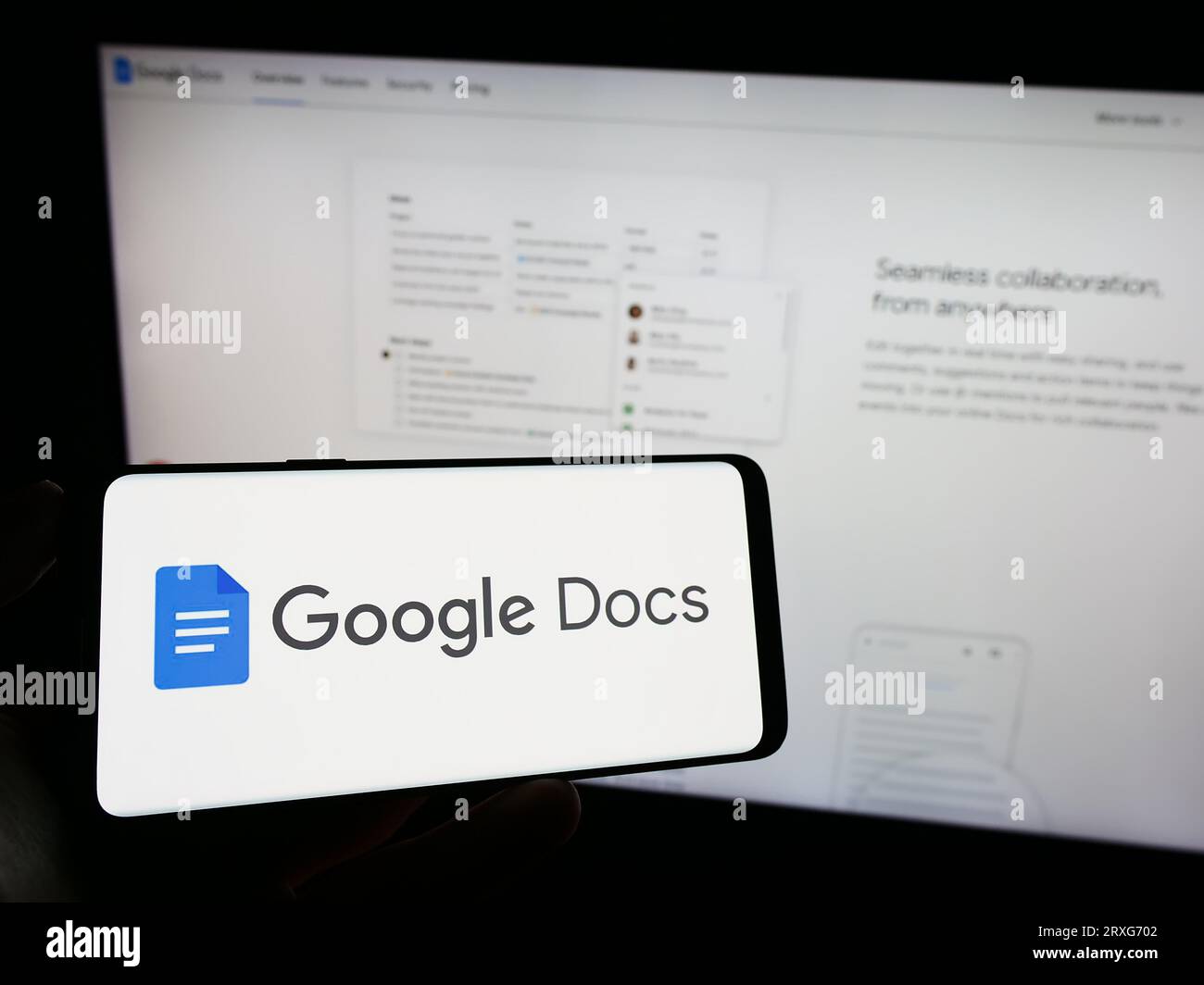 Person holding cellphone with logo of online word processing product Google Docs on screen in front of company webpage. Focus on phone display. Stock Photo