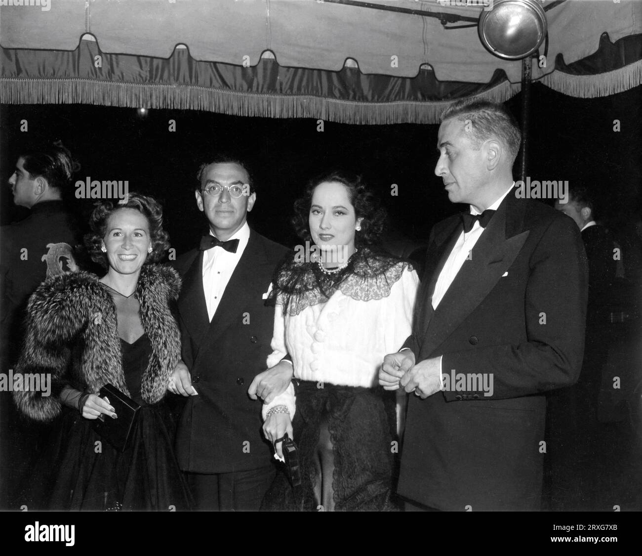 Mrs DARRYL F. ZANUCK (former silent movie actress VIRGINIA FOX) producer WILLIAM GOETZ and MERLE OBERON at an unidentified Hollywood premiere in April 1943 Stock Photo