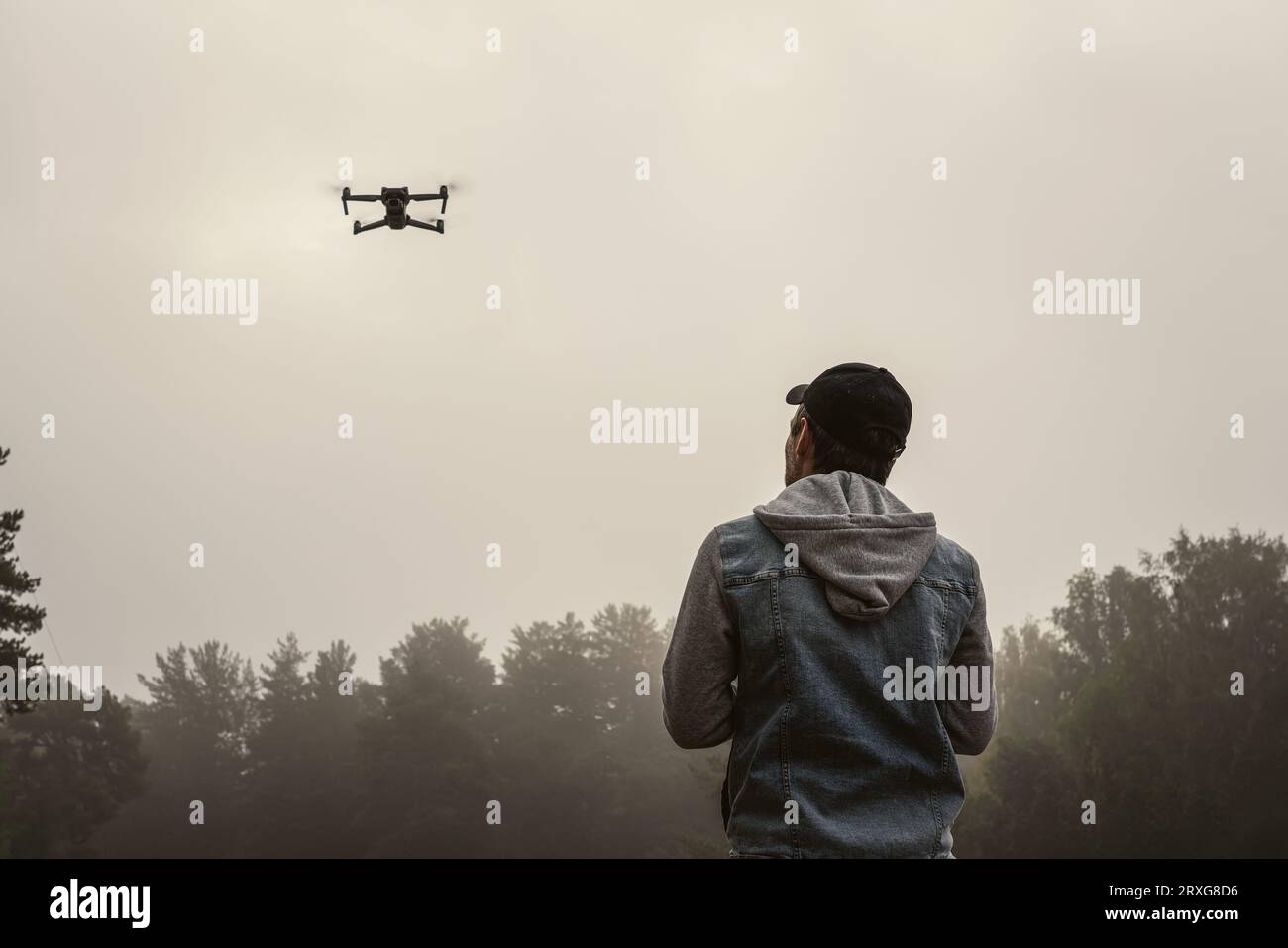 Professional photographer taking photos from drone. man taking aerial photos in forest. Man controlling his drone on background of mountain forest. Stock Photo