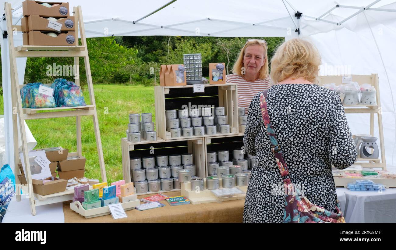 Countryside fete stall holder selling candles, soaps and aromatherapy products, Cornwall, UK - John Gollop Stock Photo