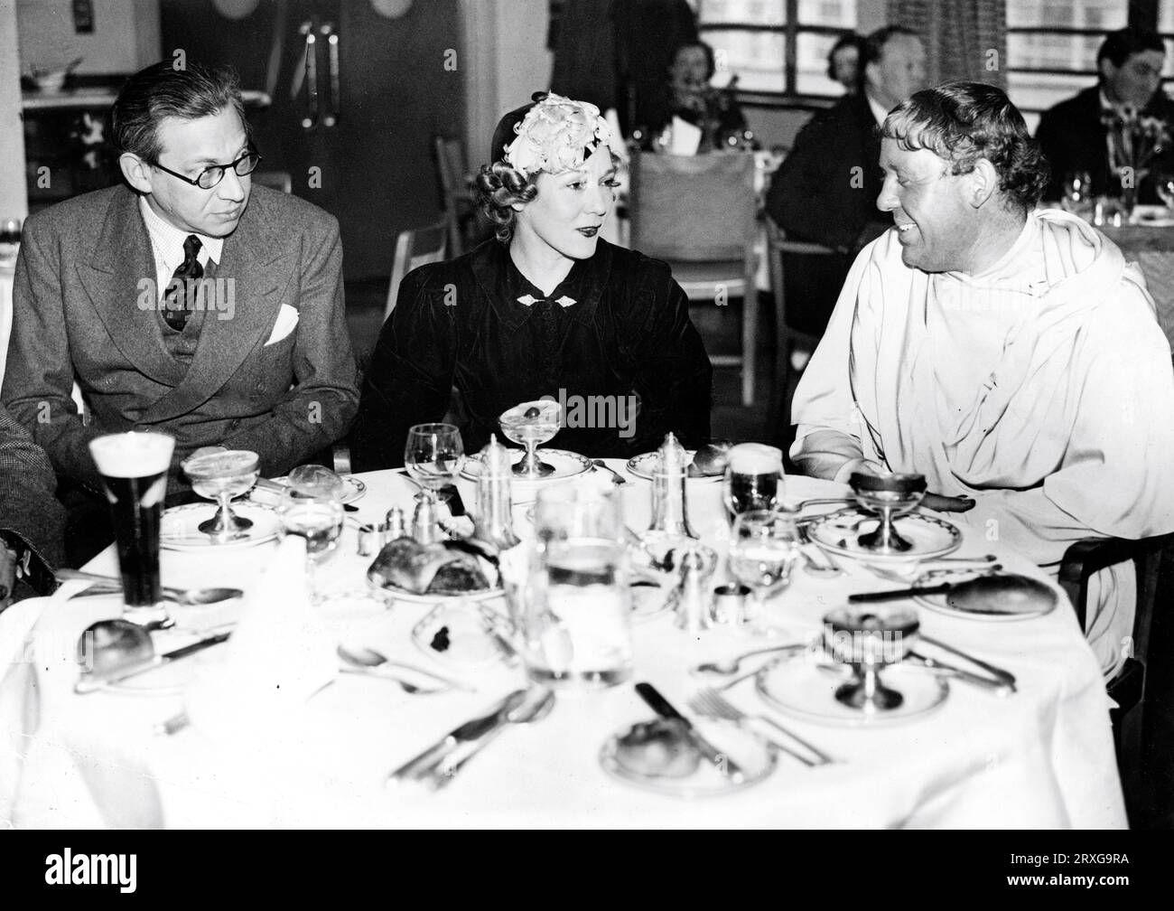 Guest MARY PICKFORD lunches with Head of London Film Productions ALEXANDER KORDA and CHARLES LAUGHTON (in costume for the subsequently abandoned film I, CLAUDIUS director JOSEF von STERNBERG book Robert Graves) at the restaurant at Denham Studios in England in early March 1937 publicity for London Film Productions Stock Photo