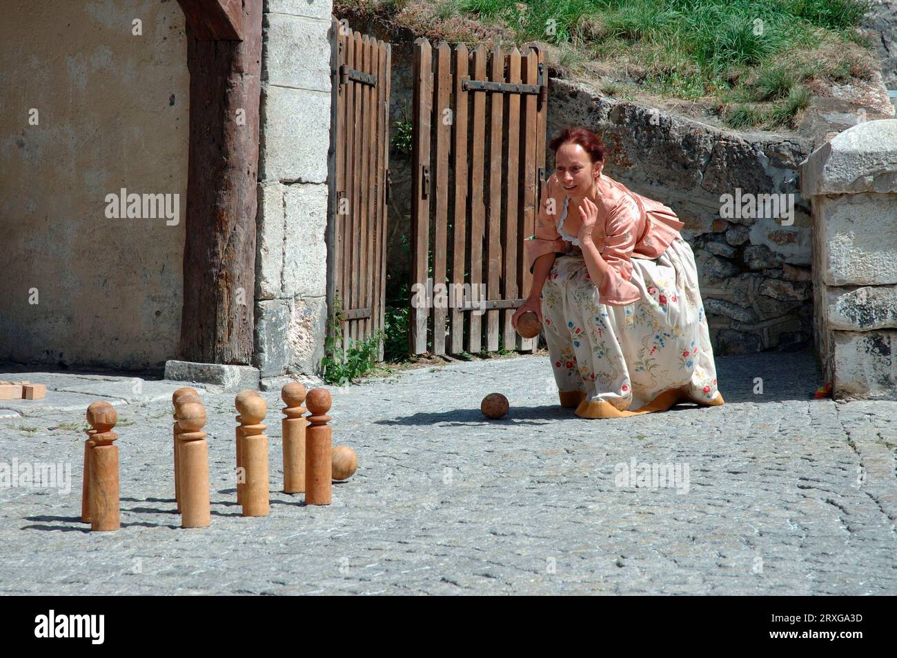 Woman in traditional traditional costume playing skittles, Briancon, France Stock Photo