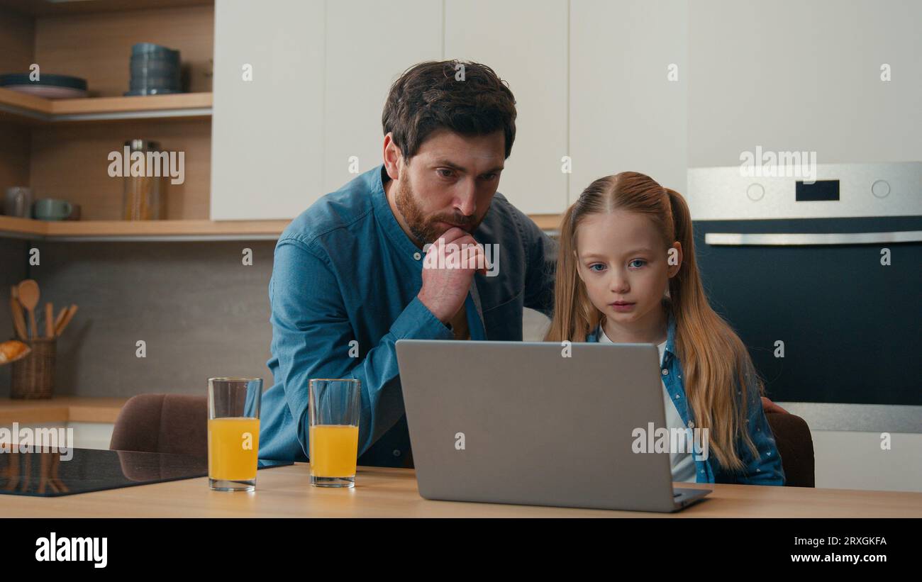 Family domestic kitchen Caucasian father help online homework little girl pupil school child daughter together e-learning using computer parental Stock Photo