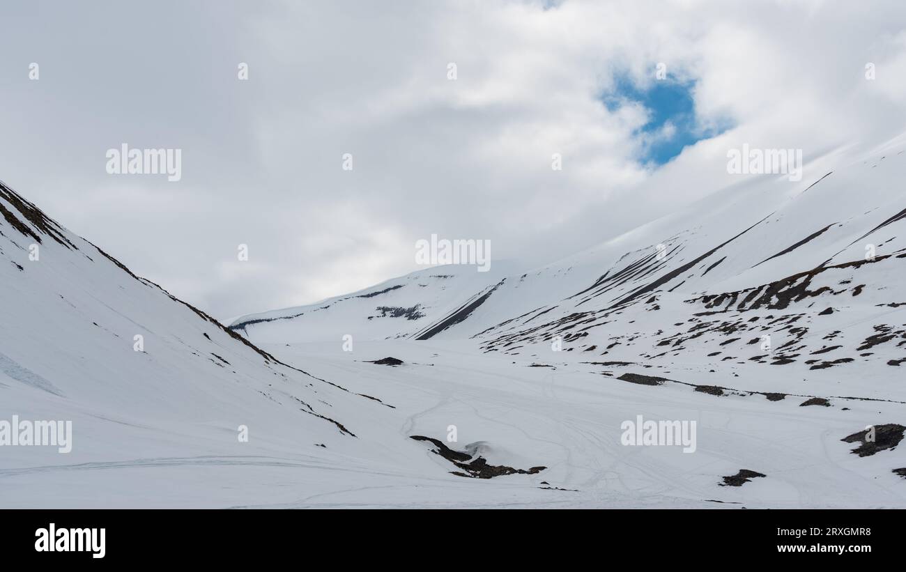 Snow covered mountains in cloudy weather with snowmobile tracks and ...