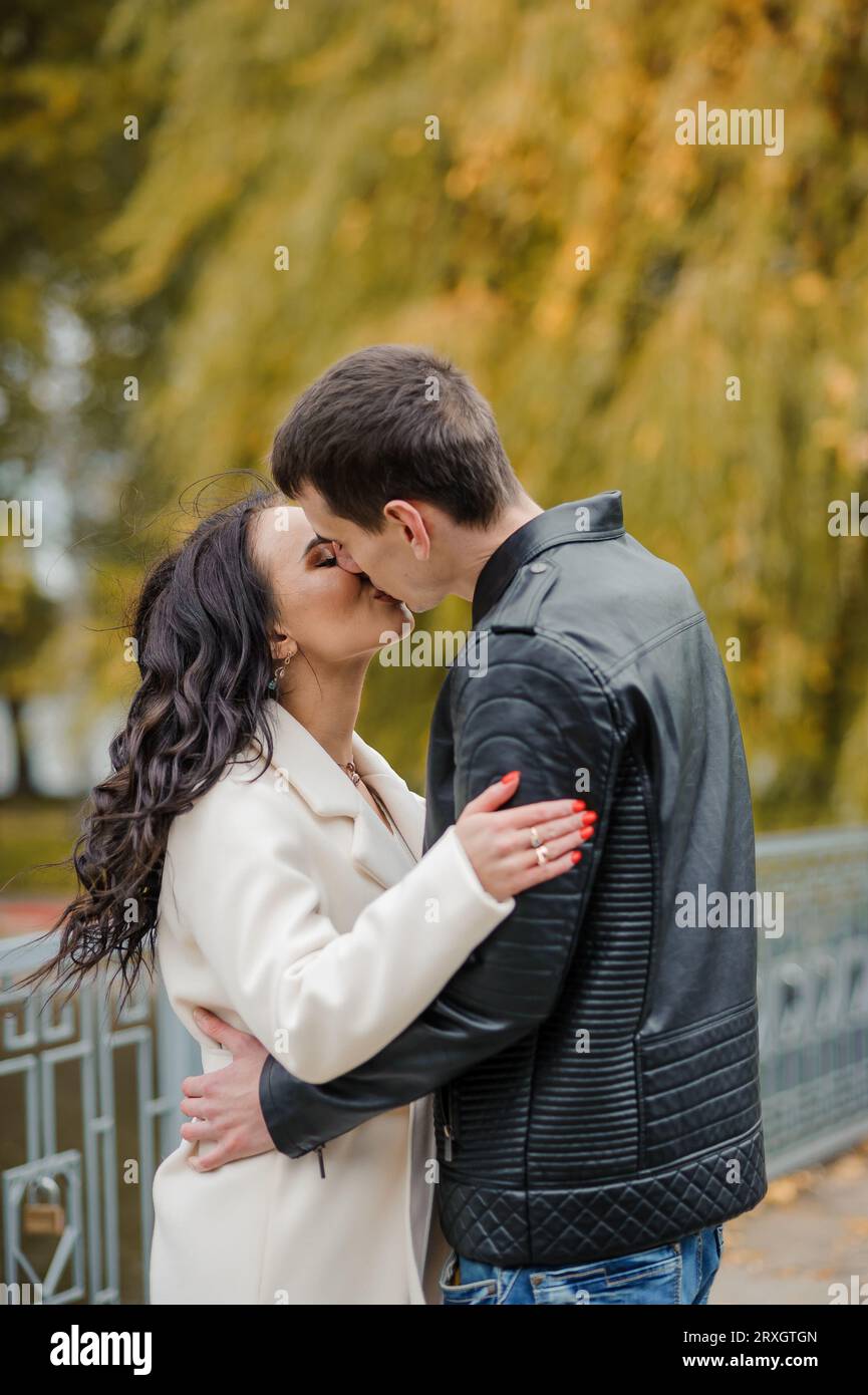 A man hugs his pregnant wife. A man in a black jacket hugs and kisses a ...