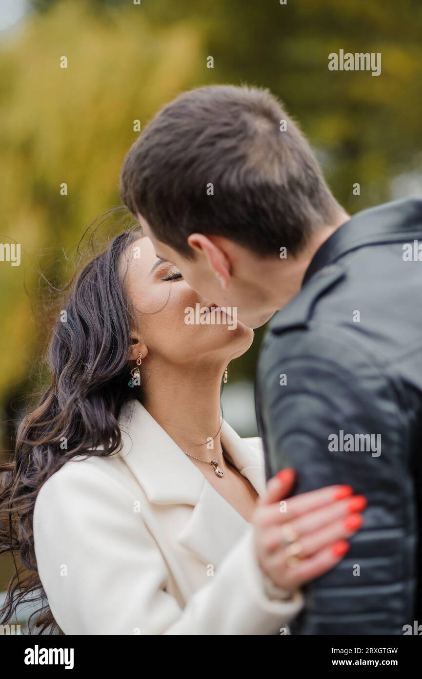 A man hugs his pregnant wife. A man in a black jacket hugs and kisses a ...