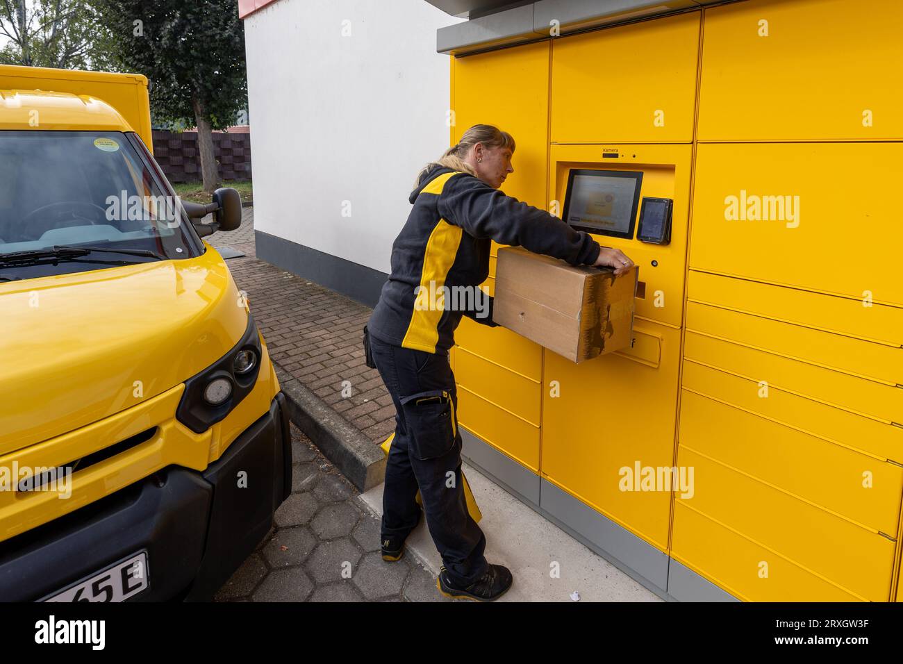 25 September 2023, Saxony, Meißen: A Deutsche Post AG postwoman scans a parcel (returned items) at a postal station in Meißen, Saxony. In addition to parcels, letters can also be posted at this location. Photo: Daniel Schäfer/dpa Stock Photo