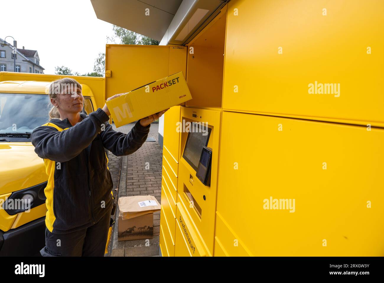 25 September 2023, Saxony, Meißen: A Deutsche Post AG postwoman removes a parcel (returned items) at a postal station in Meißen, Saxony. In addition to parcels, letters can also be posted at this location. Photo: Daniel Schäfer/dpa Stock Photo