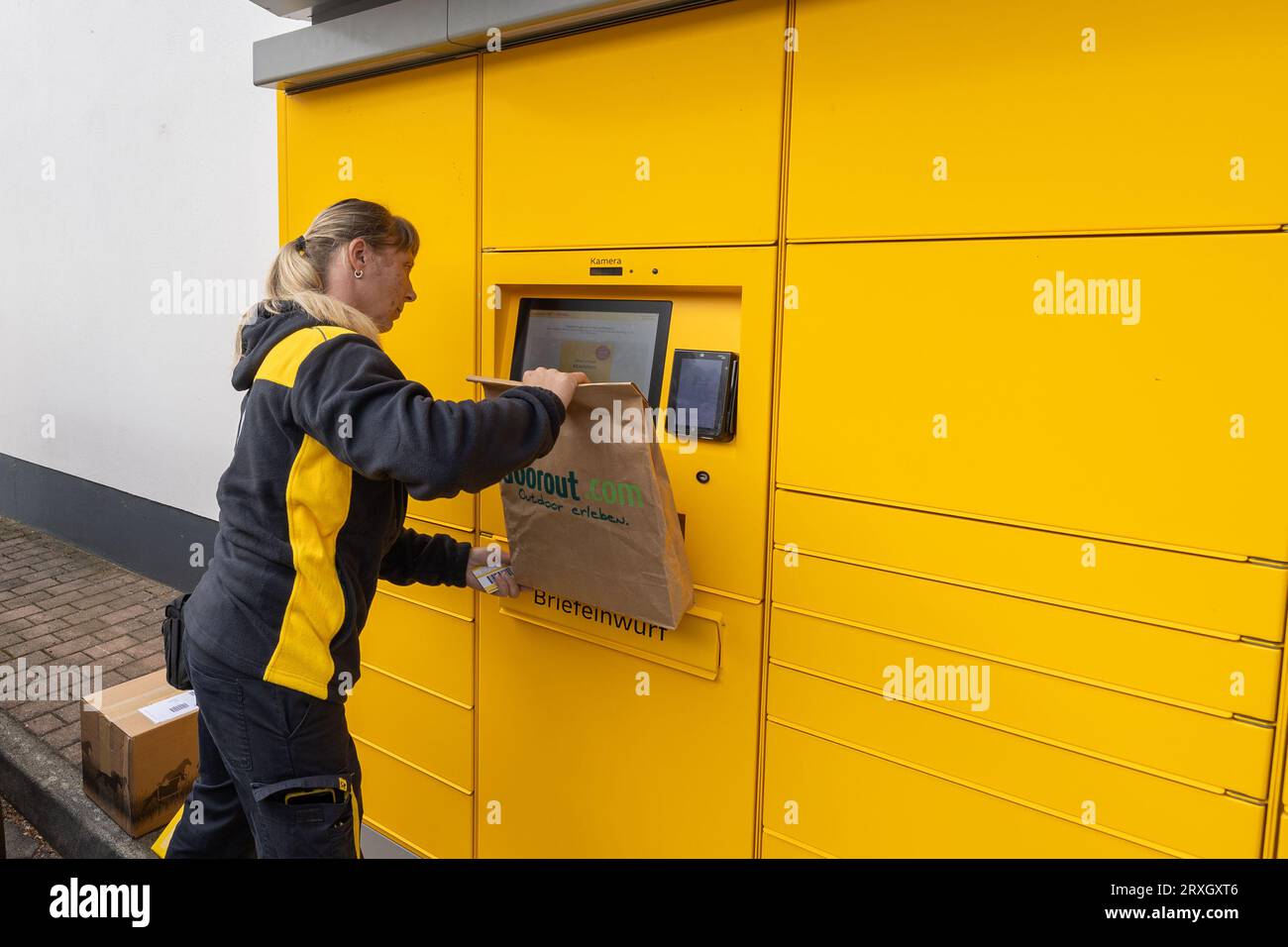 25 September 2023, Saxony, Meißen: A Deutsche Post AG postwoman scans an item at a postal station in Meißen, Saxony. In addition to parcels, letters can also be posted at this location. Photo: Daniel Schäfer/dpa Stock Photo