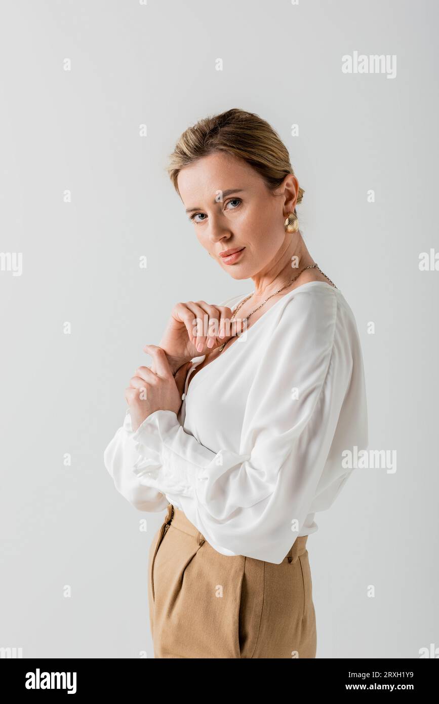 beautiful voguish blonde in pastel attire looking at camera with her