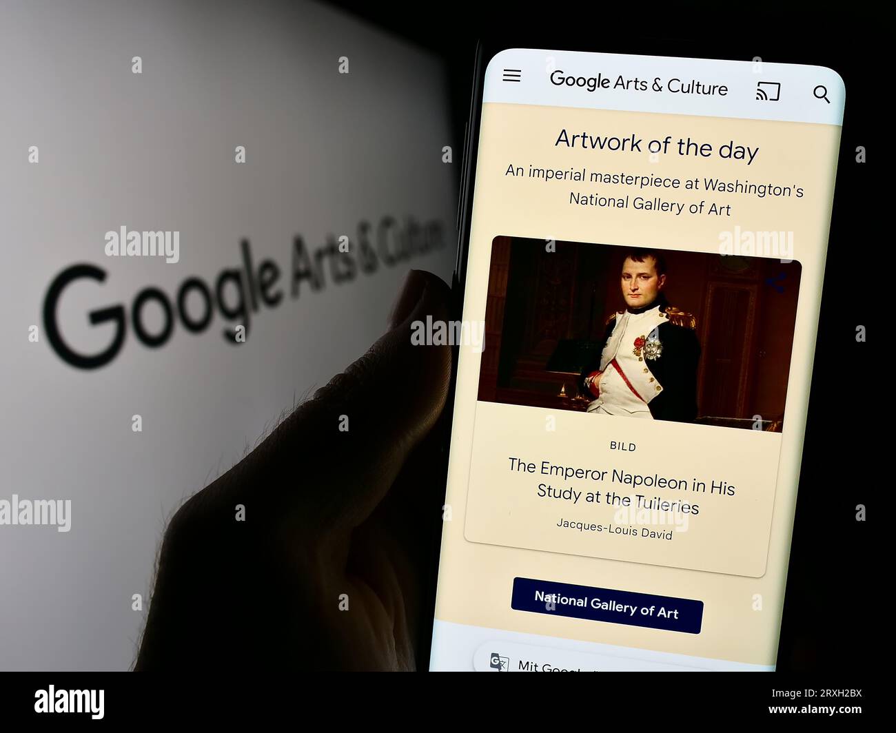 Person holding cellphone with webpage of online platform Google Arts and Culture on screen in front of logo. Focus on center of phone display. Stock Photo