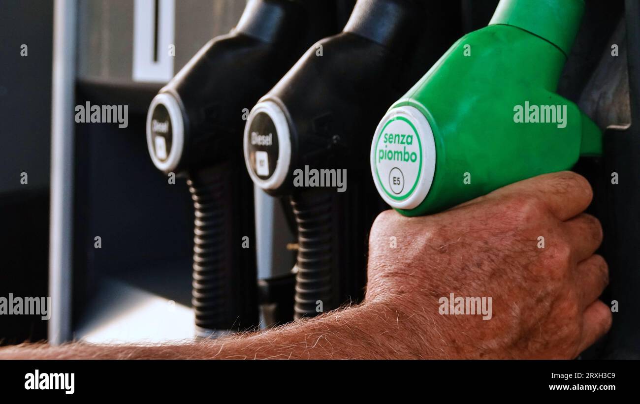 Hand of a man holding a green gasoline pump bearing the inscription