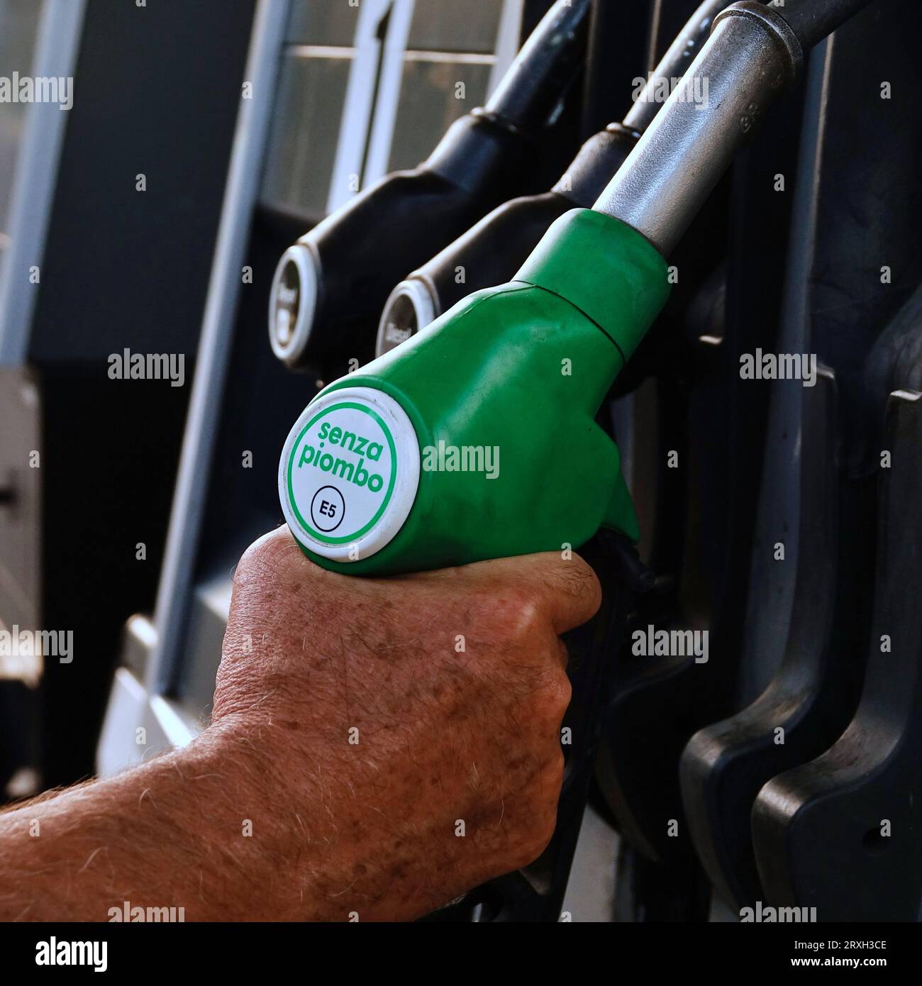 Hand of a man holding a green gasoline pump bearing the inscription