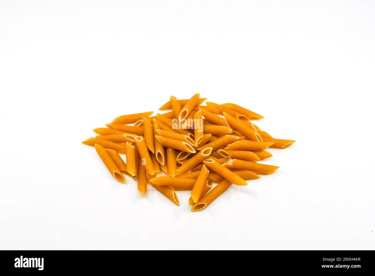 Heap of dried wholemeal penne pasta tubes isolated on a plain white background. Copy space. Stock Photo