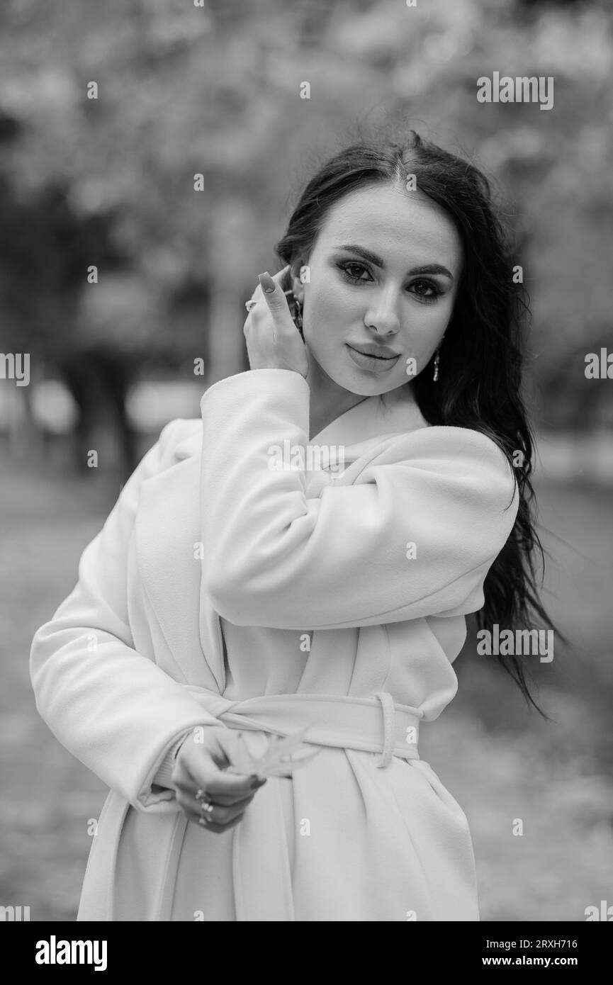Brunette girl in a white coat in an autumn park Stock Photo