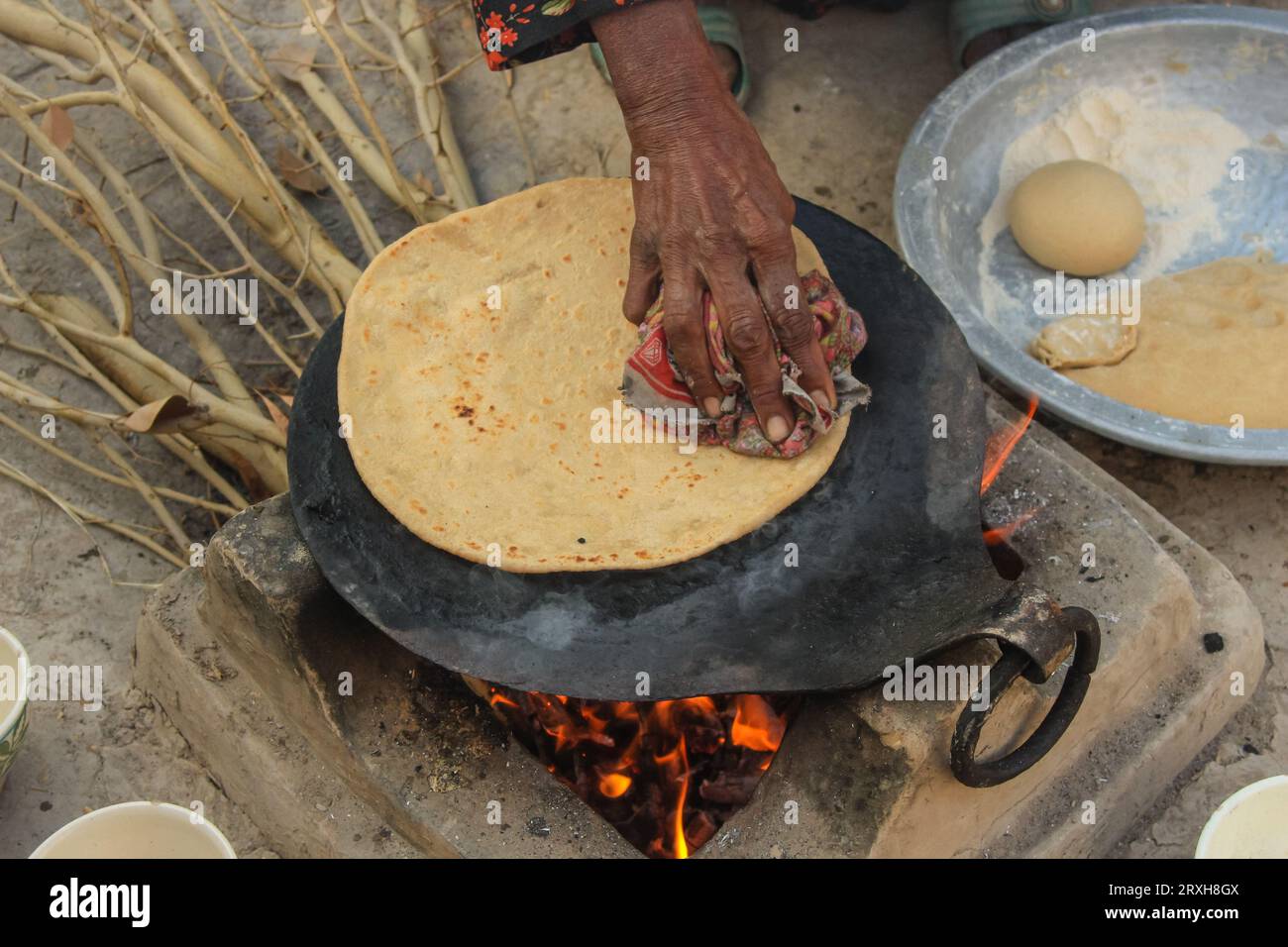 Close up of hands of an Asian female making roti in the kitchen. Concept of the rural preparation of  Pakistani or Indian chapati. Pakistani village w Stock Photo
