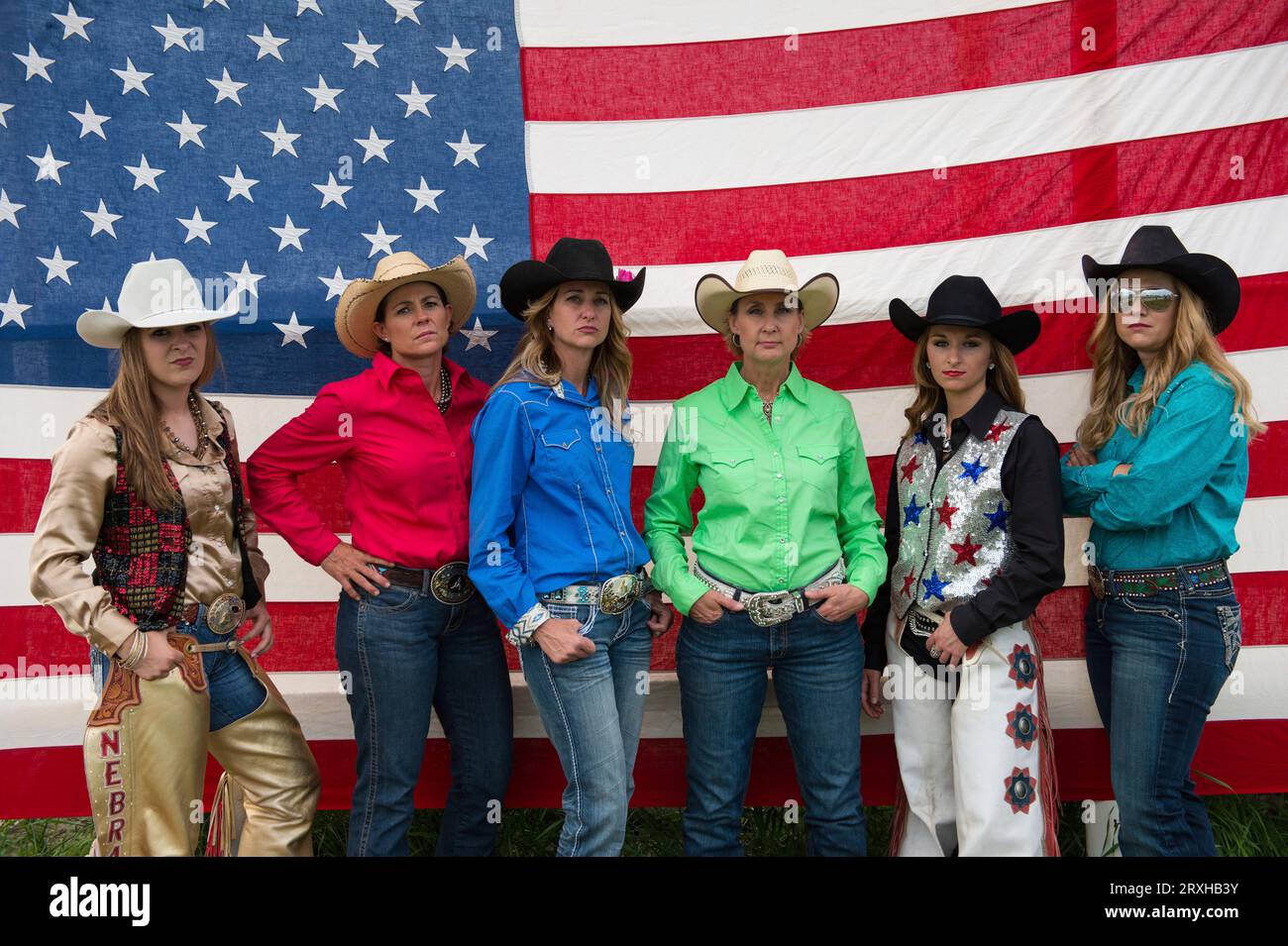 Rodeo queens pose for a portrait in front of an American flag; Burwell, Nebraska, United States of America Stock Photo