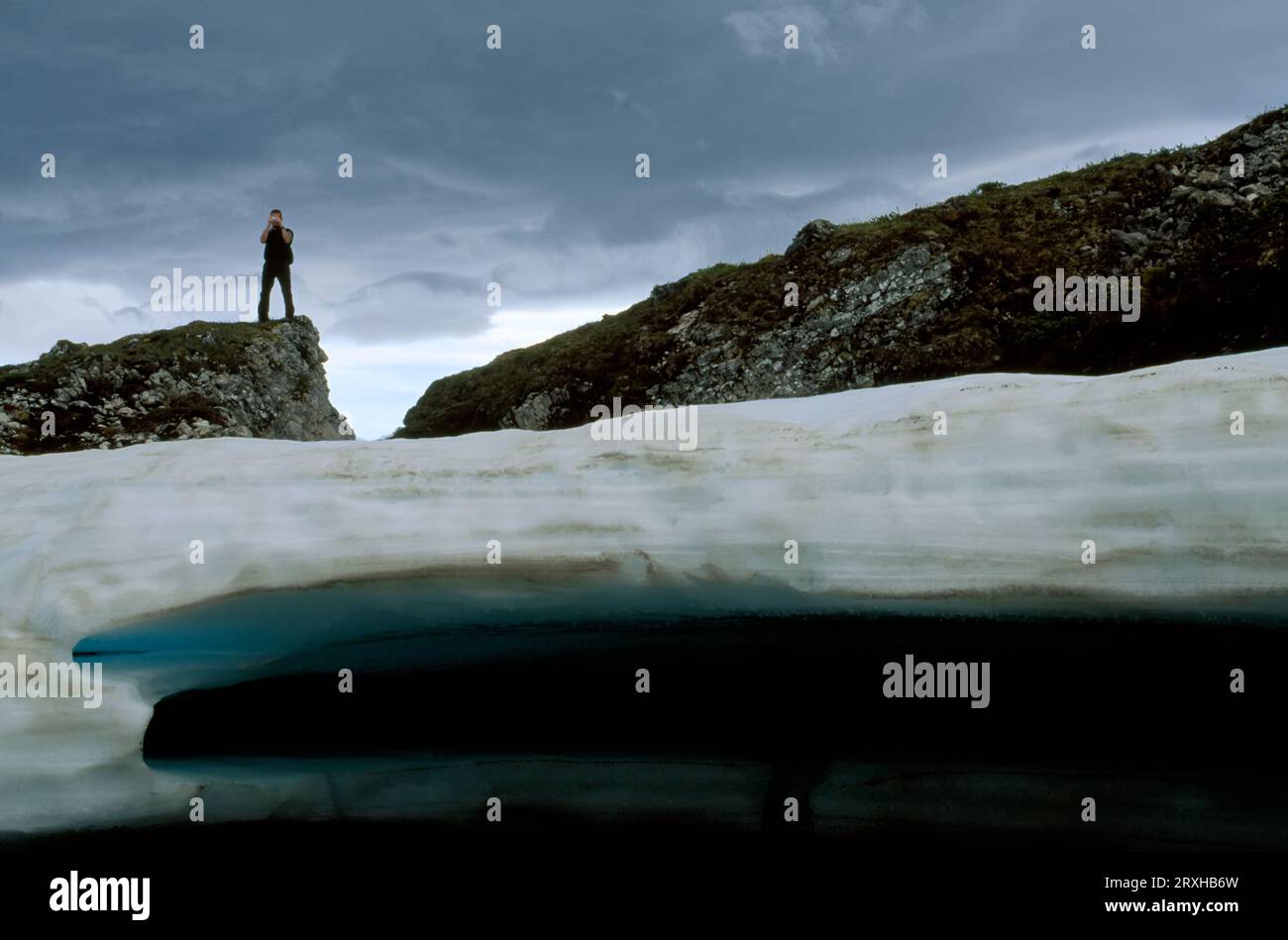 Man looks at and photographs melting ice; North Slope, Alaska, United States of America Stock Photo