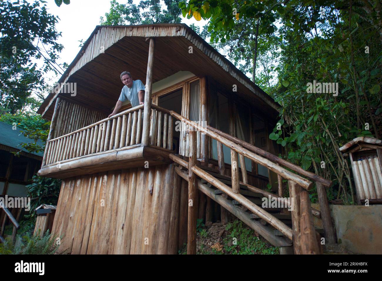 Man stands on the porch of his cabin looking down at the camera, near Bwindi Impenetrable Forest National Park in Uganda; Uganda Stock Photo