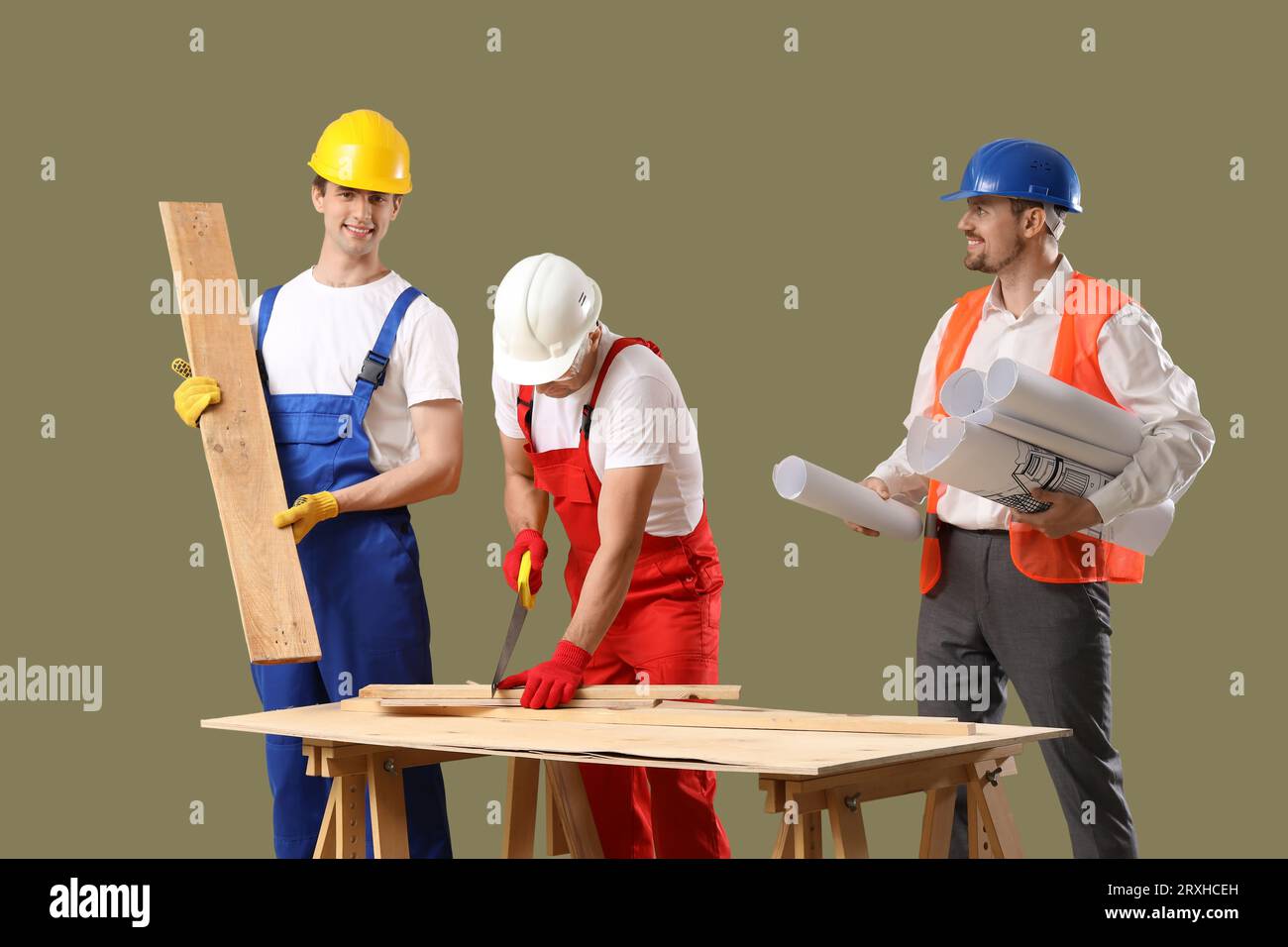 Team of male builders with wooden planks and house plans on green background Stock Photo