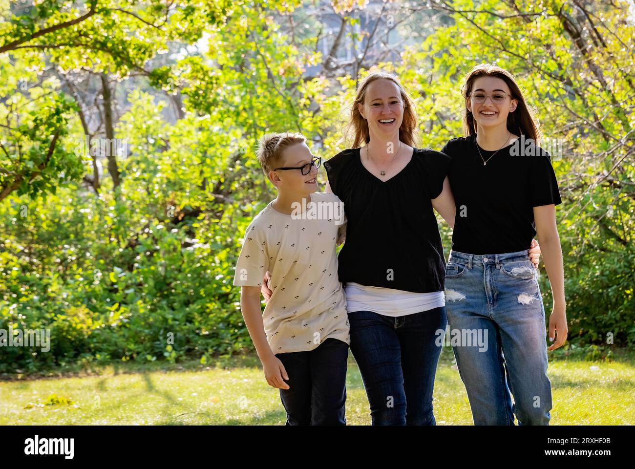 Mother spending quality time outdoors with her teenage children, walking together in a city park during a warm fall afternoon; Leduc, Alberta, Canada Stock Photo