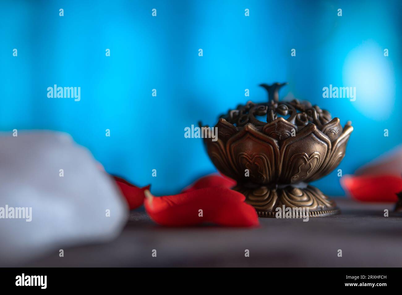 Close-up of a beautiful incense burner on a wooden table with quartz and petals, copy paste, on a blue background. spiritual themes and esoteric ritua Stock Photo