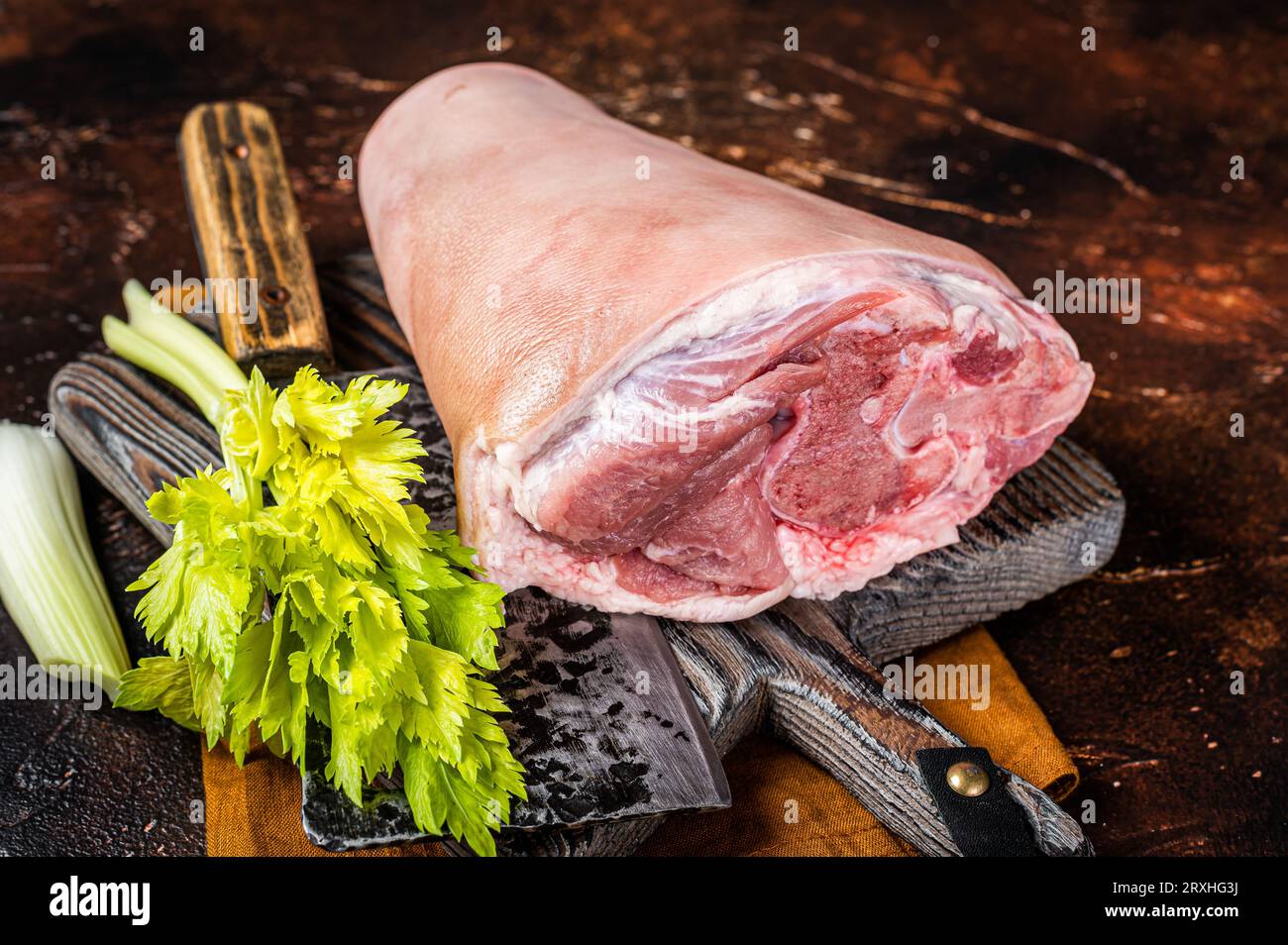 Fresh Raw pork shank knuckle on a butcher board with herbs for cooking