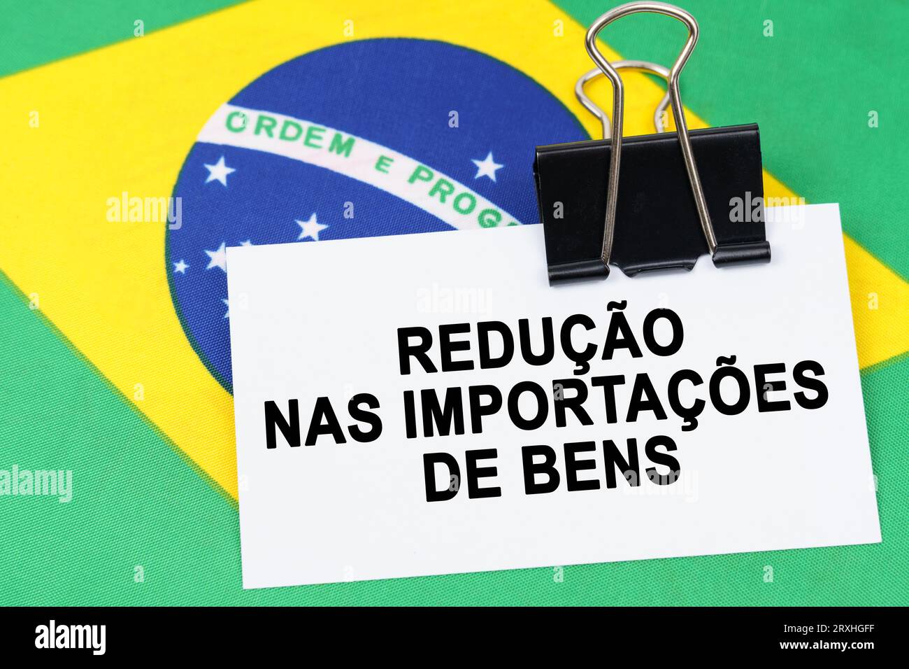 Economy and finance concept. On the flag of Brazil lies a business card with the inscription - reduction in imports of goods. Text in Portuguese. Stock Photo