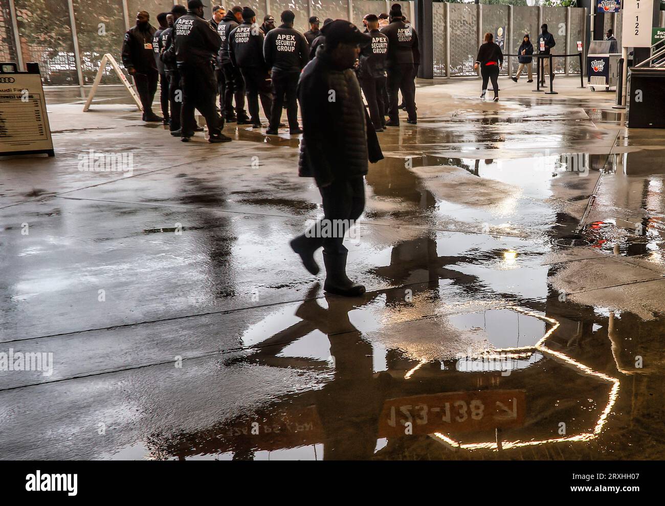 Security personnel gather in a wet stadium before a game Stock Photo