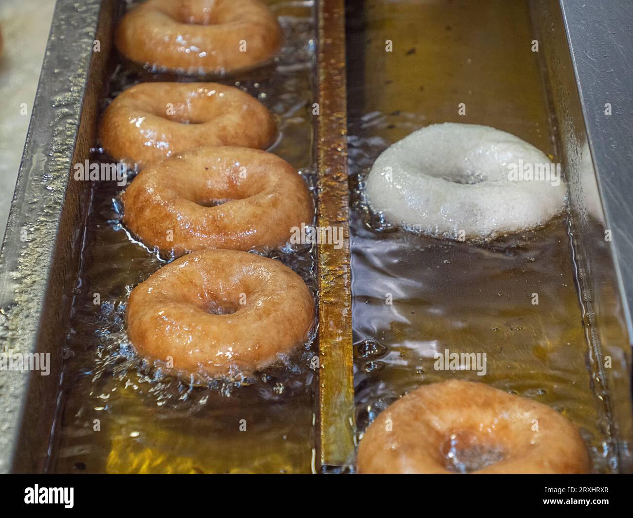 Cooking of the fried sweet tasty doughnuts in deepfryer hot oil Stock