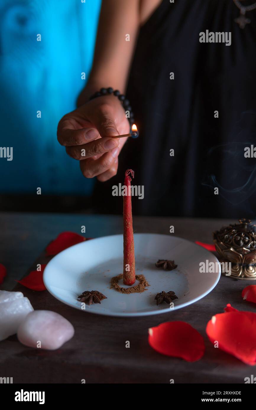 Lighting a red candle, witch on the eve of all saints eve performing a ritual, Halloween, spiritual beliefs, white magic Stock Photo