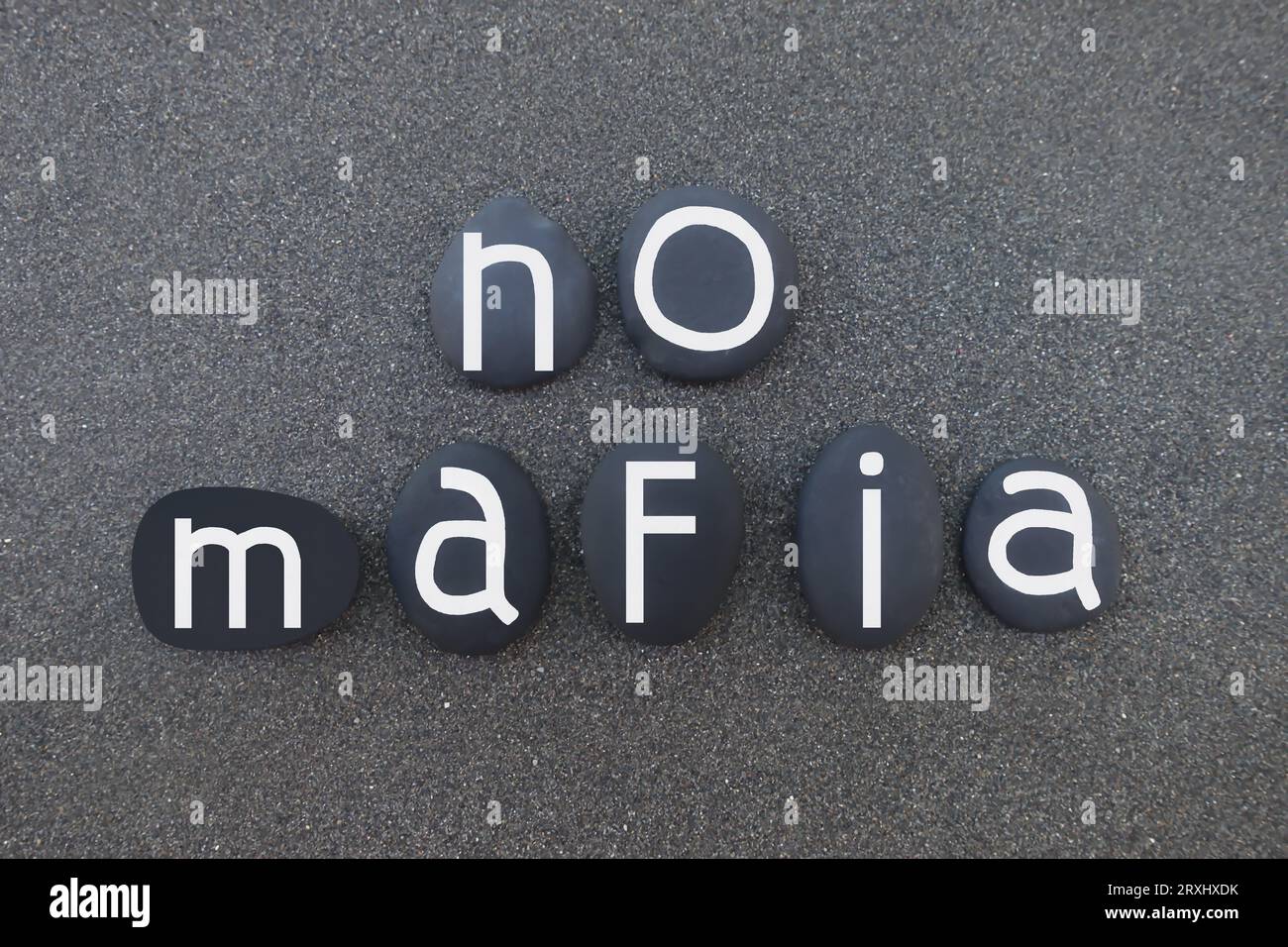 No mafia, social issue slogan composed with black painted stones over black volcanic sand Stock Photo