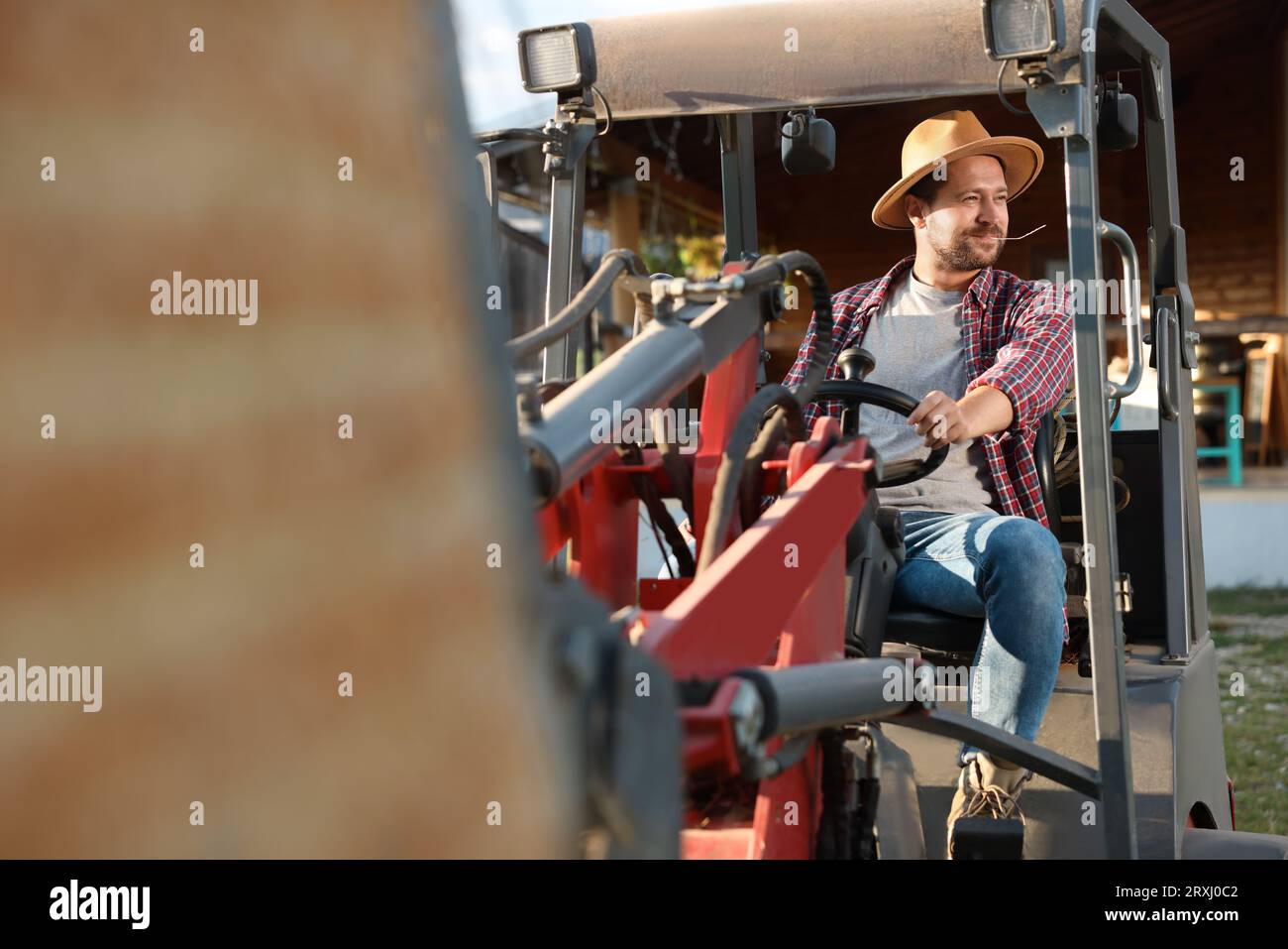 Farmer in loader transporting hay outdoors. Agriculture equipment Stock