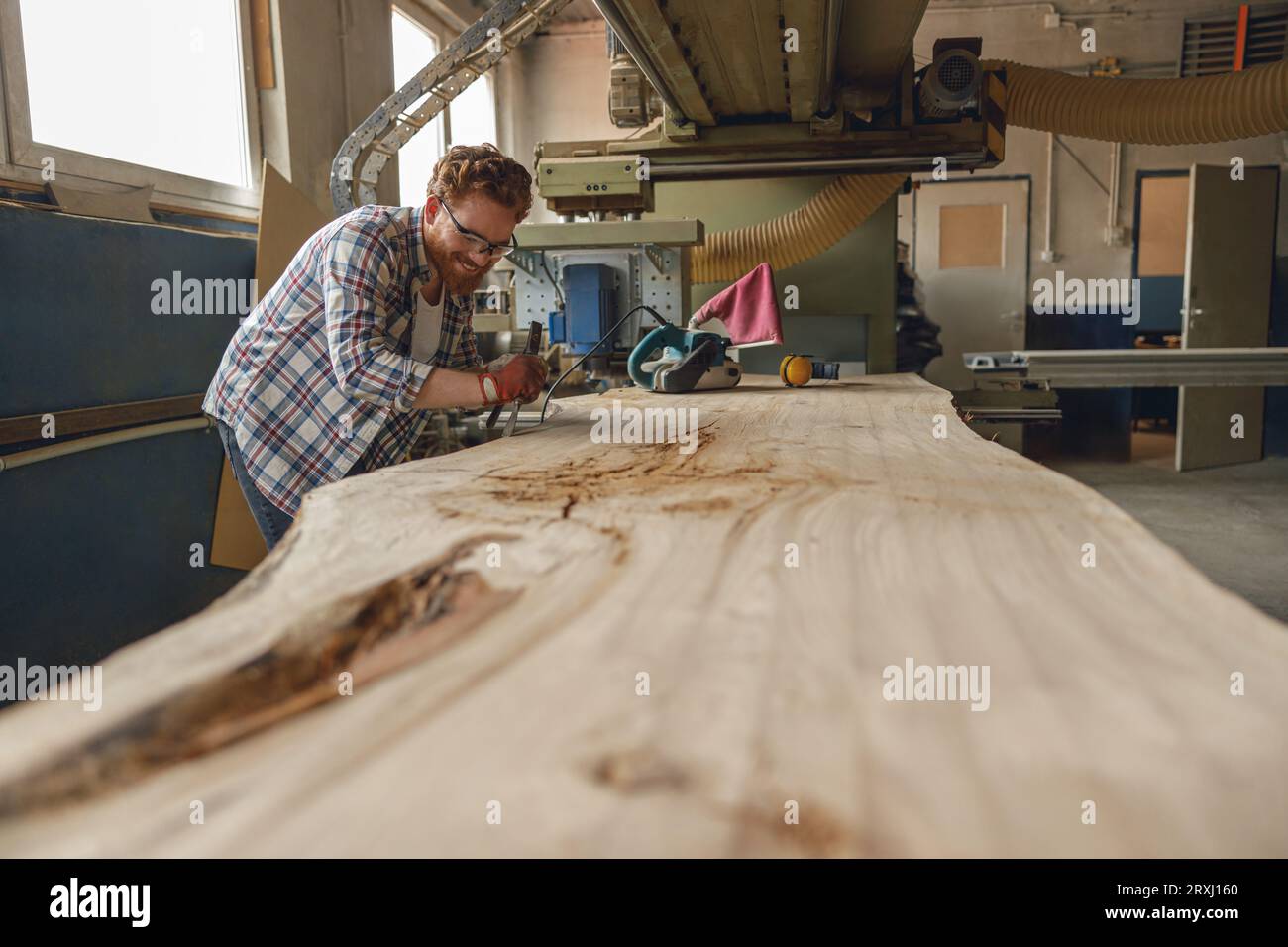 Professional craftsman working with chisel while cutting wooden plank ...