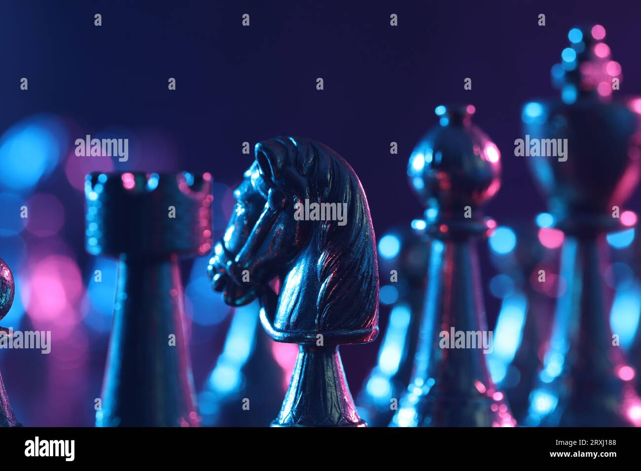 Chess pieces in color light against blue background, closeup Stock Photo