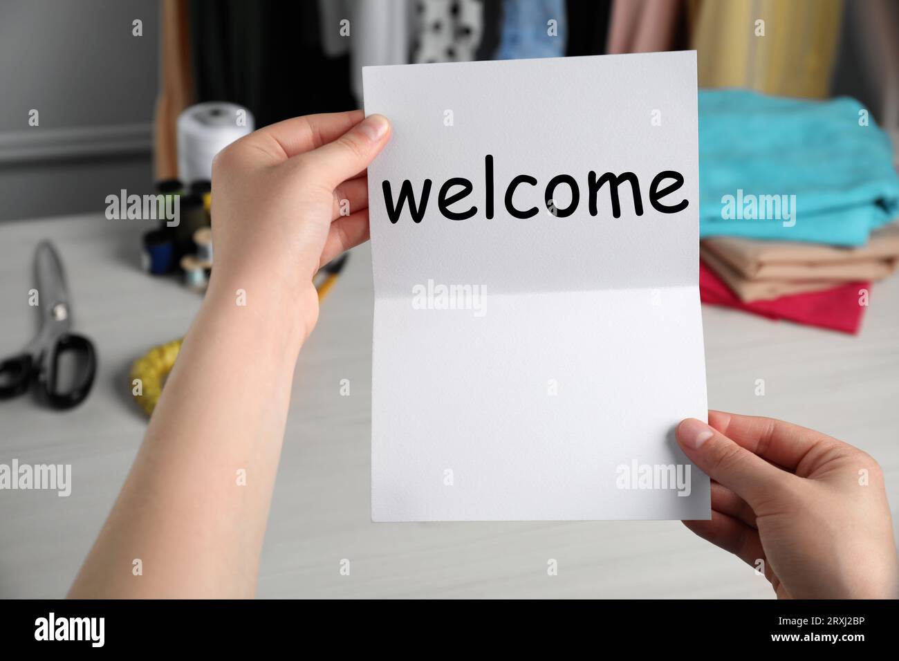 Seamstress paper with word Welcome at table in atelier, closeup Stock Photo