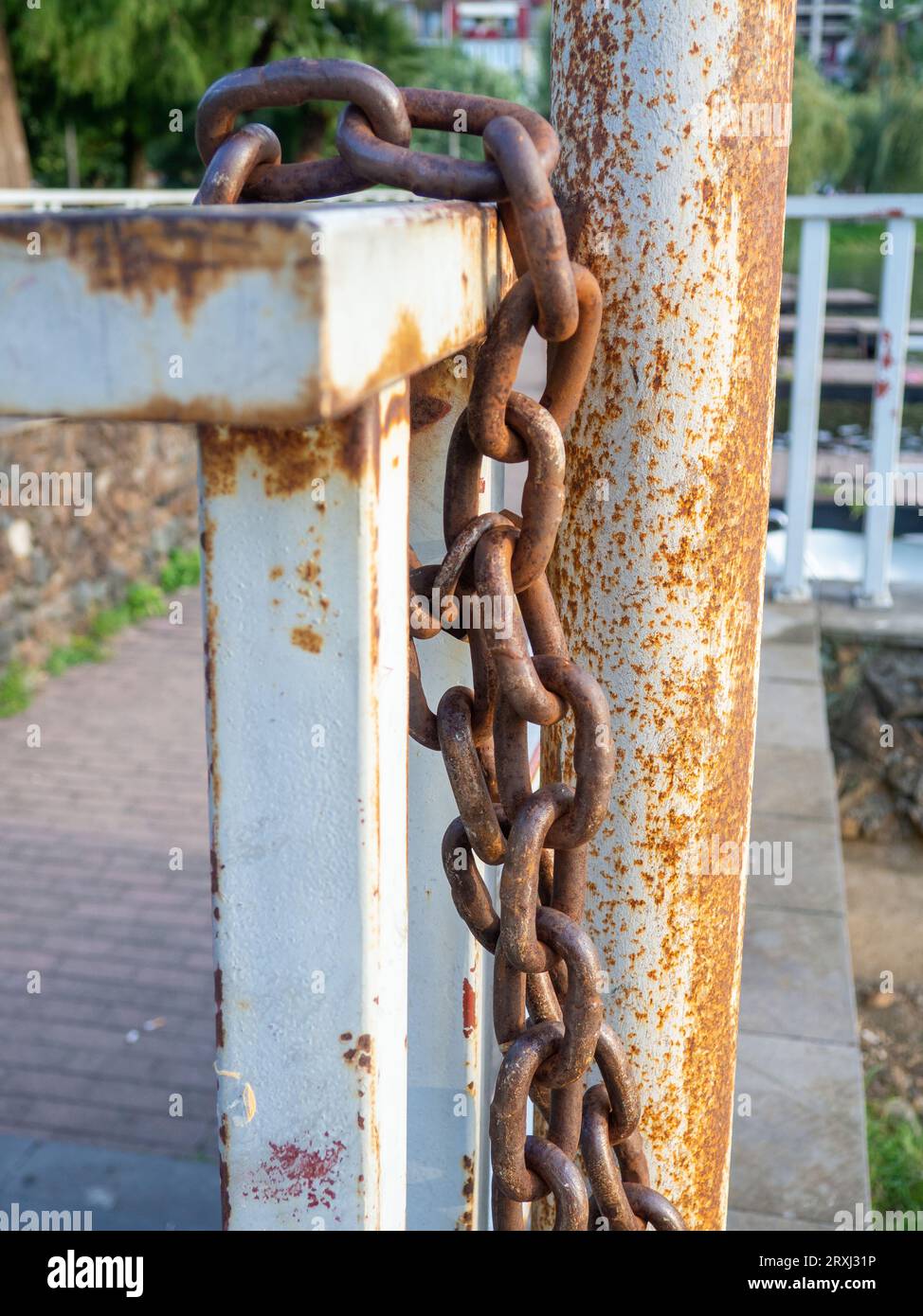 rusty chain is tied to a metal railing. Boat mooring. Reliable old chain. wound metal Stock Photo