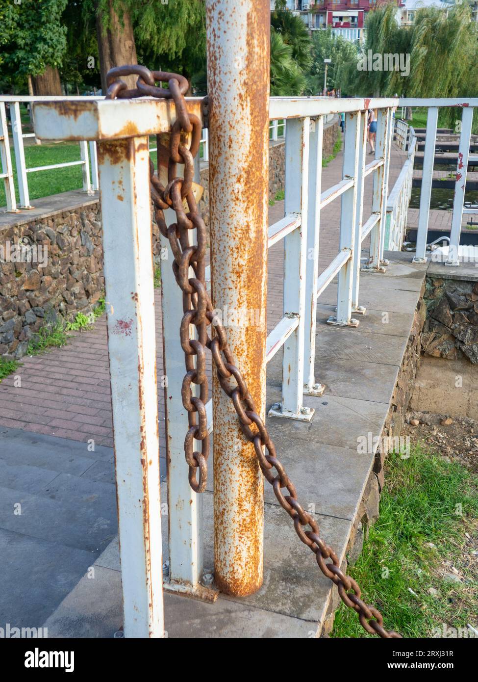 rusty chain is tied to a metal railing. Boat mooring. Reliable old chain. wound metal Stock Photo