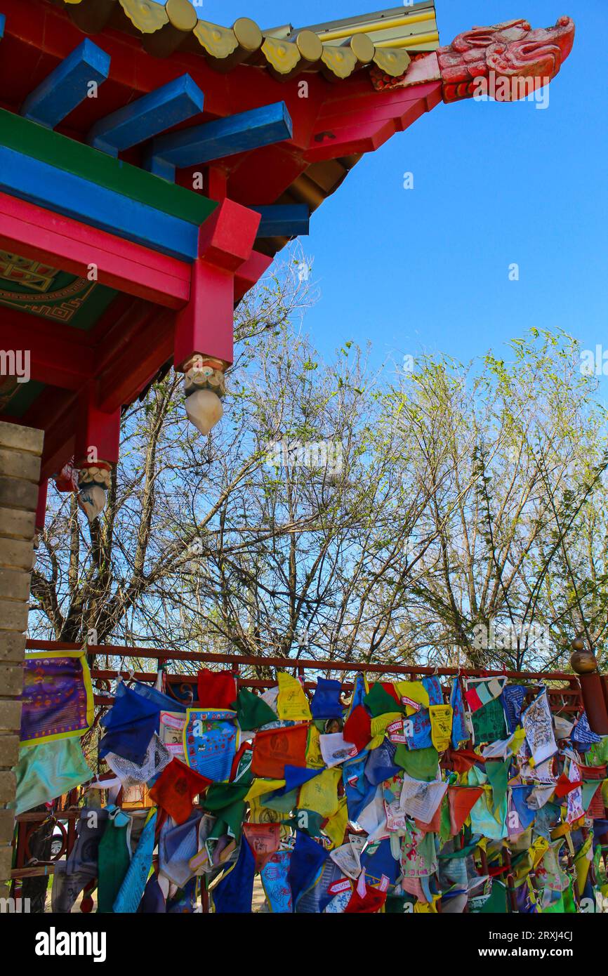 Tibetan praying flags and the roof of the gates at the Golden Abode of Buddha Shakyamuni. Elista, Republic of Kalmykia, Russia, blue sky with copy spa Stock Photo