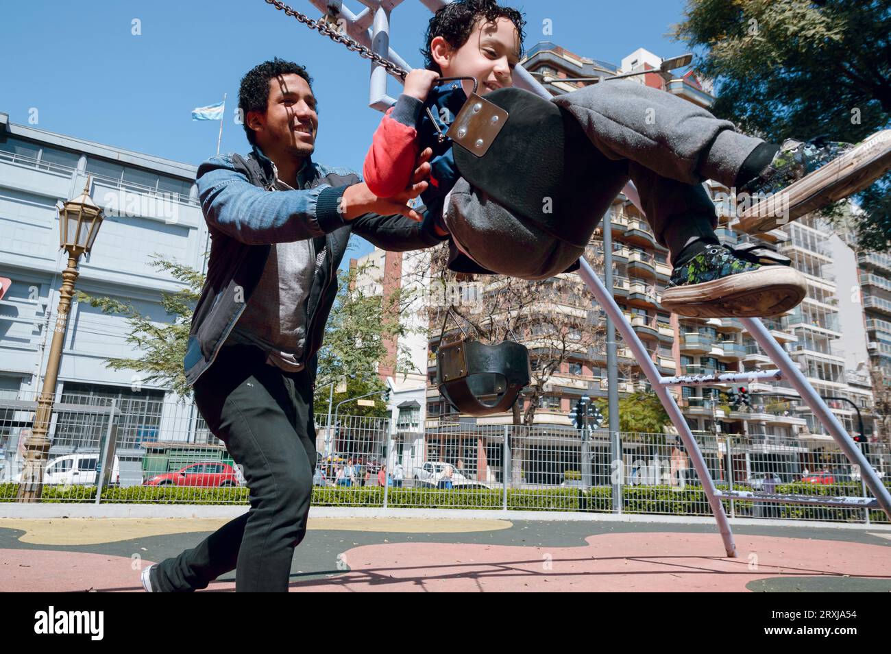 Venezuelan Latin Afro single father playing with his son on swing in ...