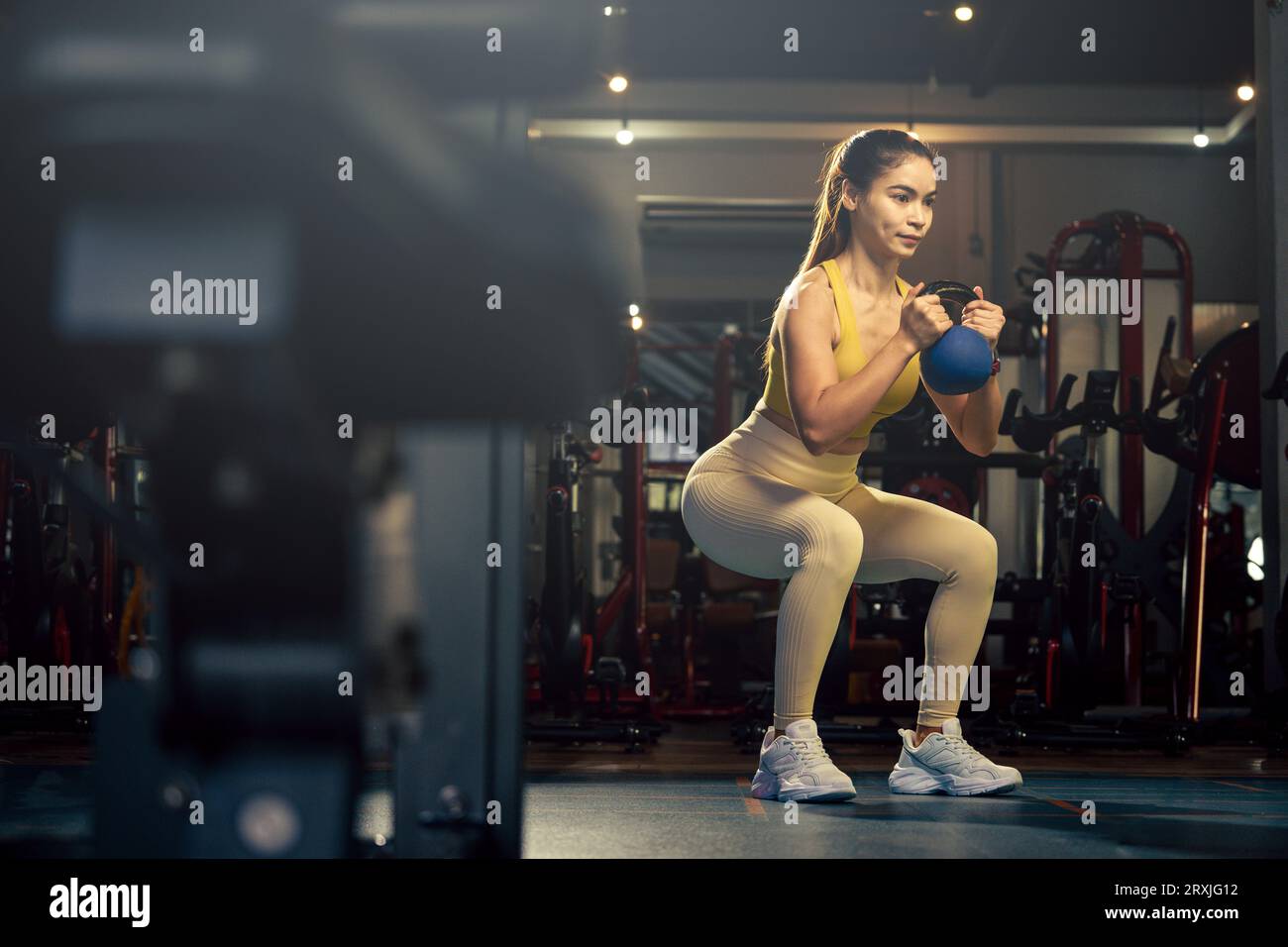 Young woman exercise workout at gym fitness training sport with kettlebell weight lifting. Stock Photo