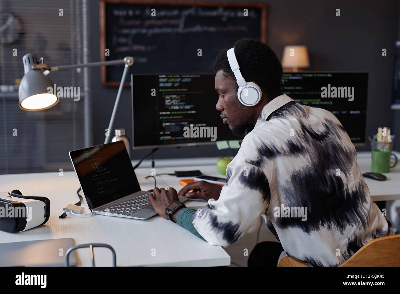 Serious programmer in wireless headphones developing new program on computer while working in IT office Stock Photo