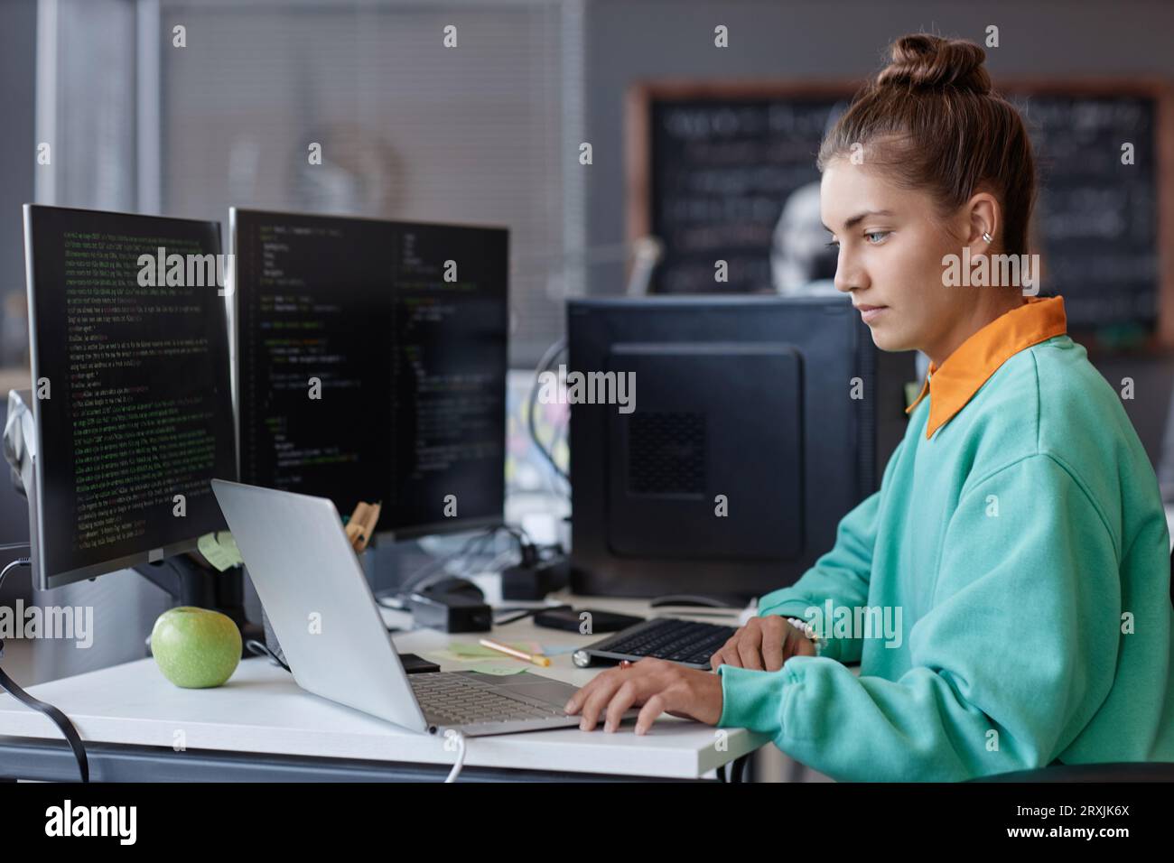 Young developer developing program on computer during her work in IT office Stock Photo